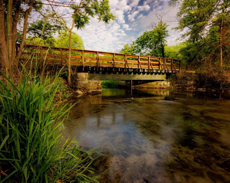 Letort Spring Run flowing under a foot bridge as it winds through a quiet and peaceful meadow. By Jay Himes Photo